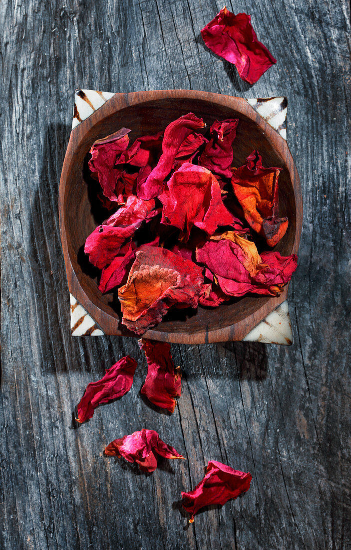 Red rose petals in a wooden bowl