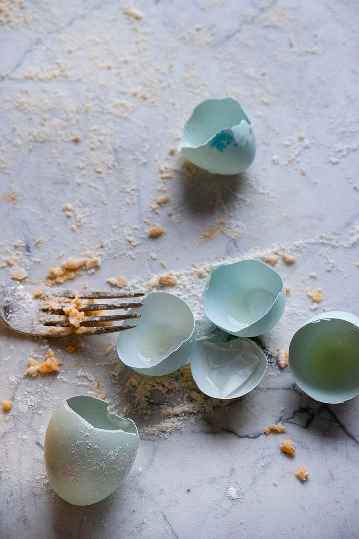 Empty Araucana egg shells and pasta on a fork against a marble background
