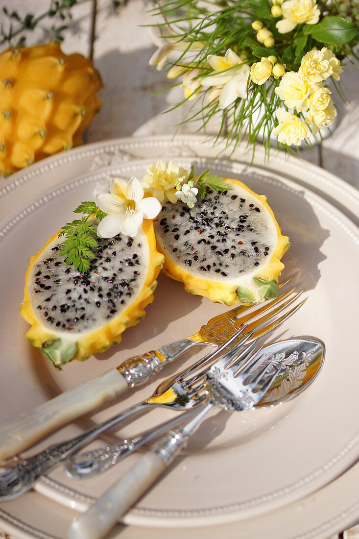 Halbierte gelbe Drachenfrucht mit Silberbesteck auf Teller