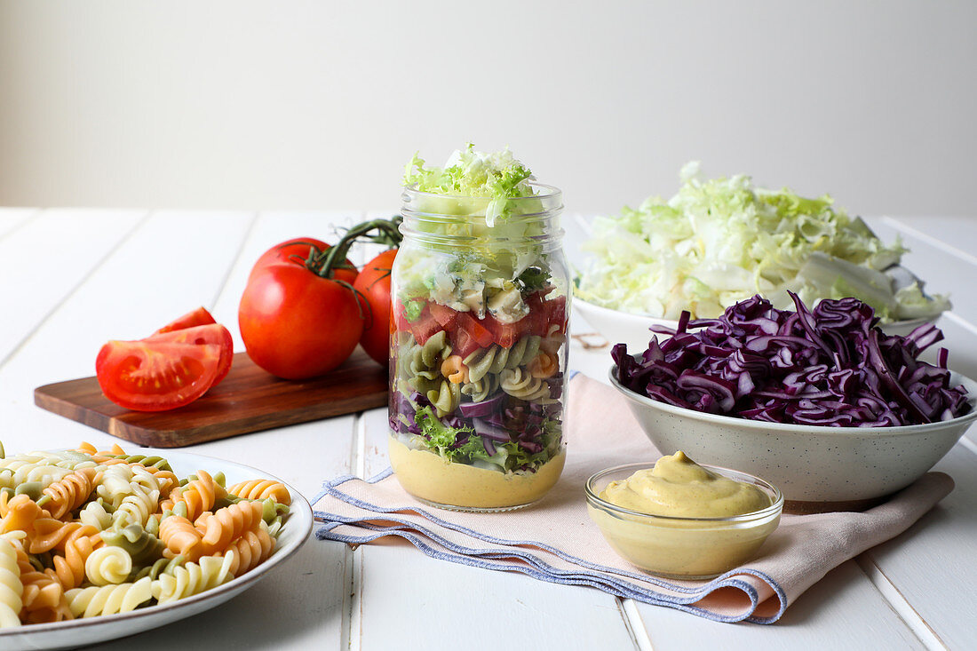 Yummy pasta with fresh vegetables and sauce placed inside jar