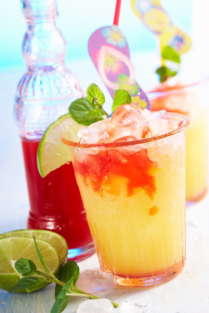 Sommerlicher Cocktail mit Pfirsichlikör, Orangensaft, Limette und Erdbeersirup