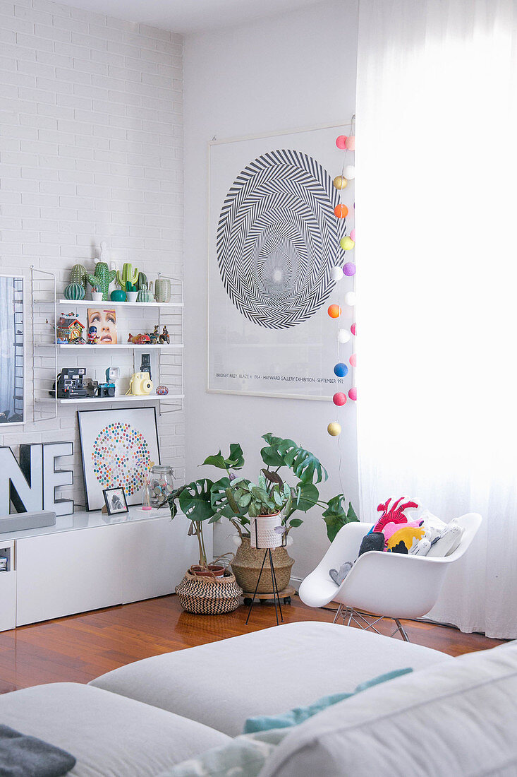 Shell chair, houseplants and low sideboard in white living room