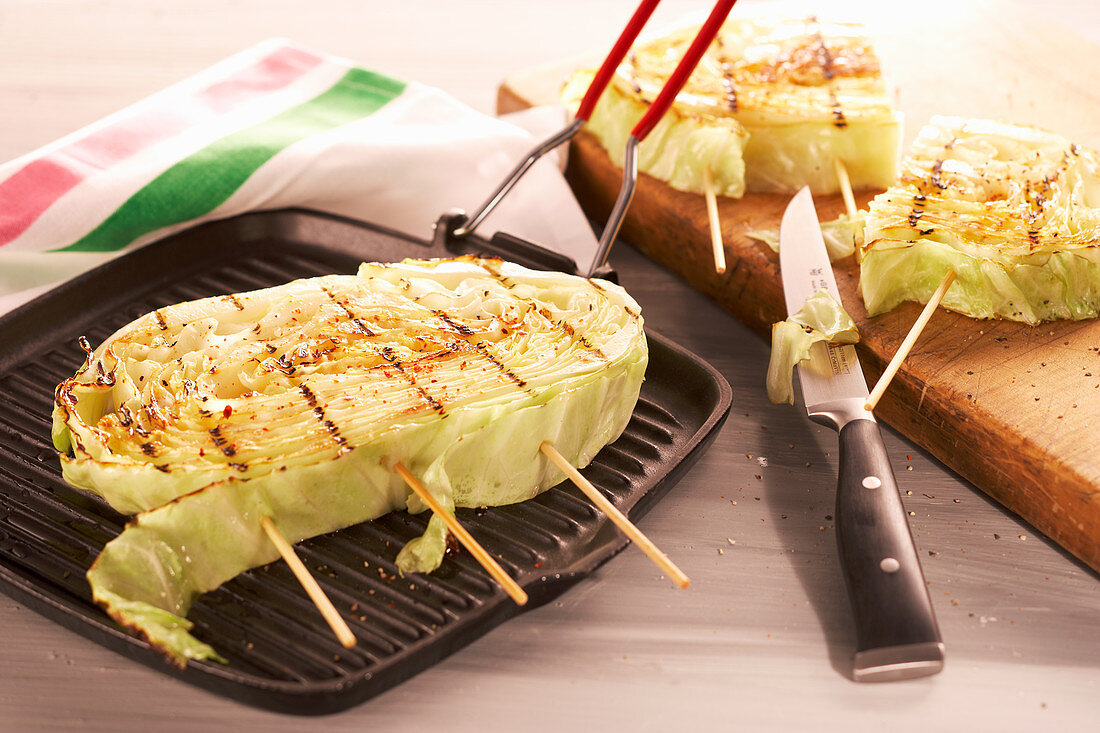 Sliced, grilled shite cabbage in a grill pan with a knife