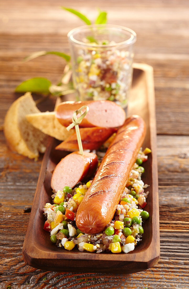 Grilled sausage with sweetcorn and pea relish on a wooden tray