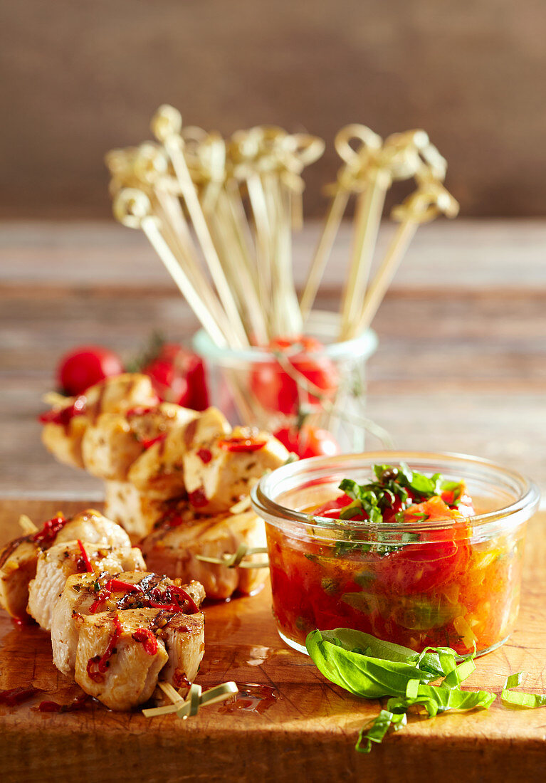 Grilled, marinated chicken skewers with cherry tomato sauce and basil