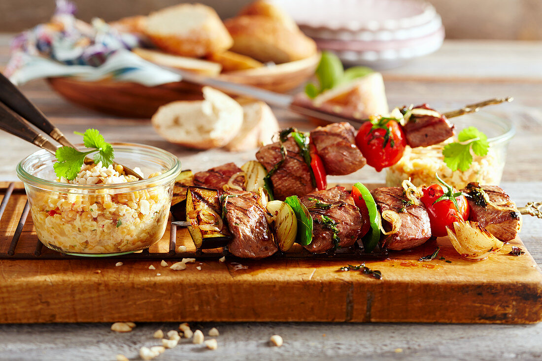 Grilled Arabic lamb skewers with a red lentil salad and white bread on a wooden board