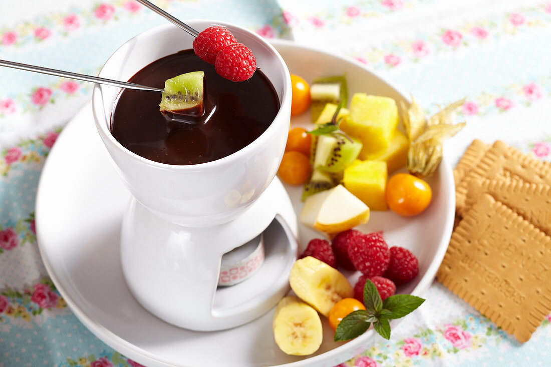 A mini chocolate fondue for dessert with fresh fruit and biscuits