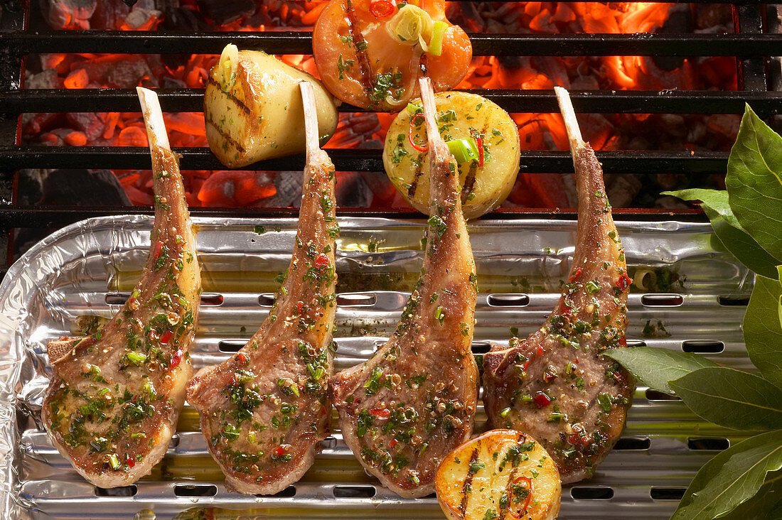 Marinated, grilled lamb chops in an aluminium tray with potatoes and tomatoes