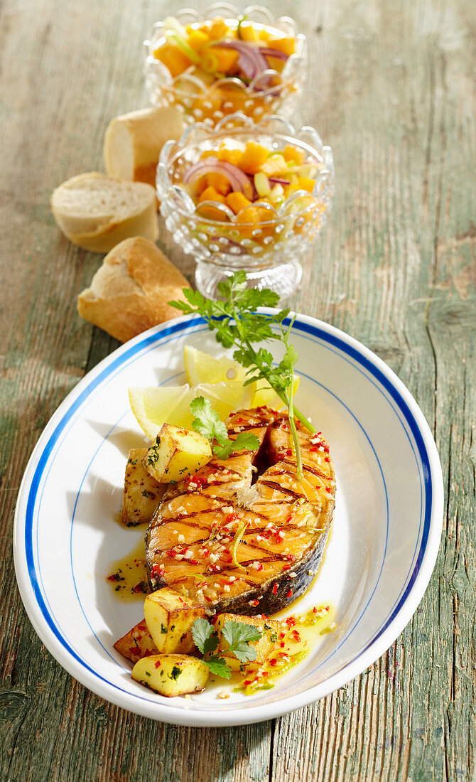 Spicy-marinated, grilled salmon steak with a papaya salad and fried potatoes