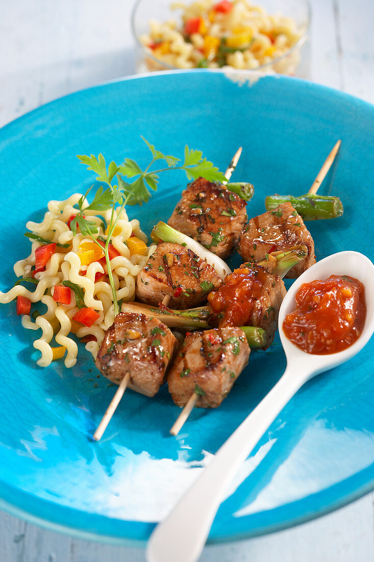Grilled turkey skewers with a spoonful of tomato chutney and pasta salad
