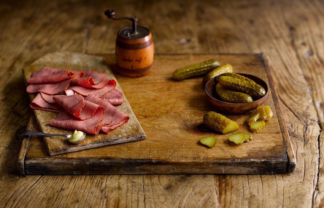 Pastrami and gherkins on a wooden cutting board