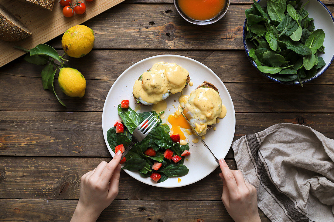 Hands of person eating full meal of scrambled eggs on bread