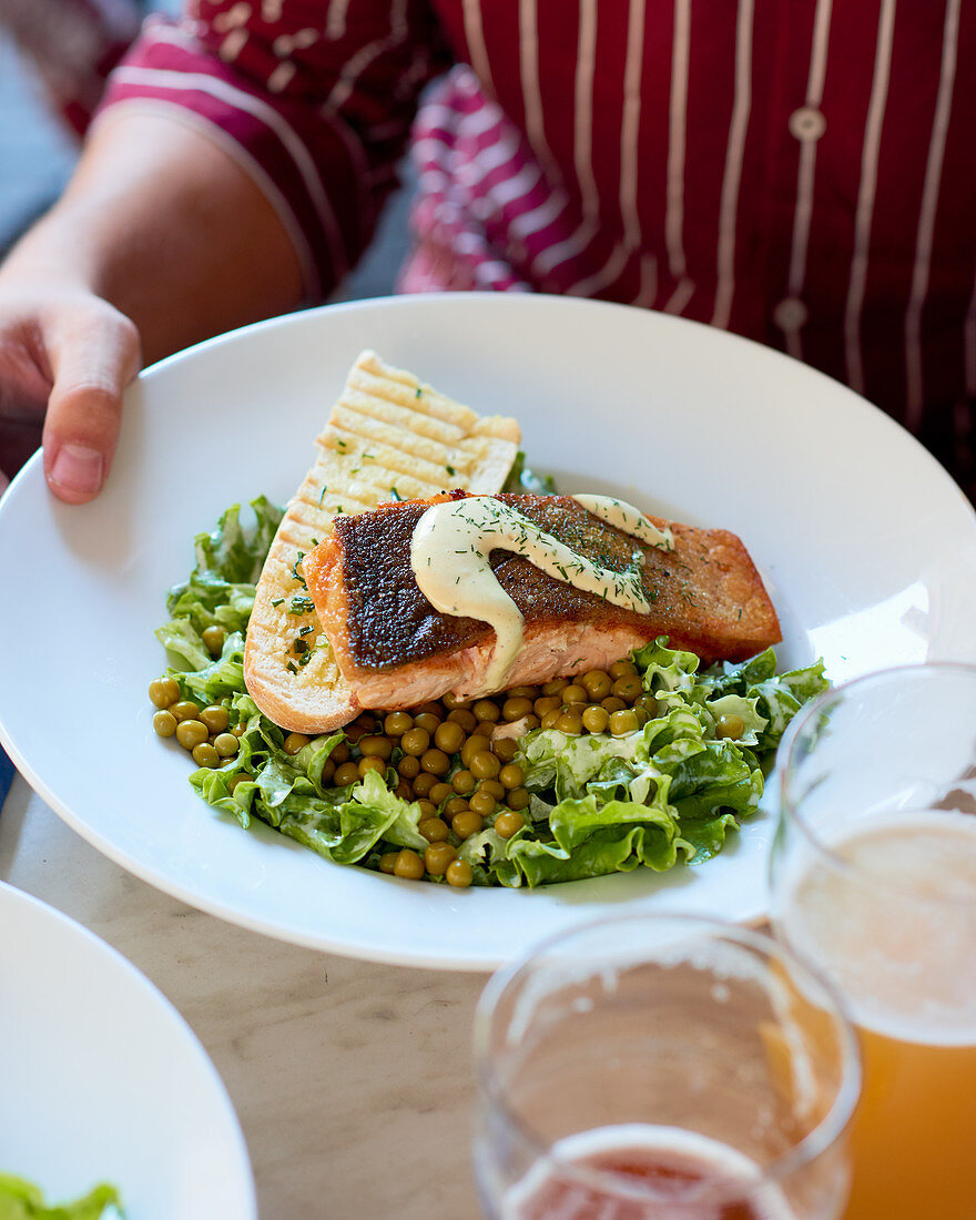 Grüner Salat mit Erbsen, gebratenem Lachs und gegrilltem Baguette