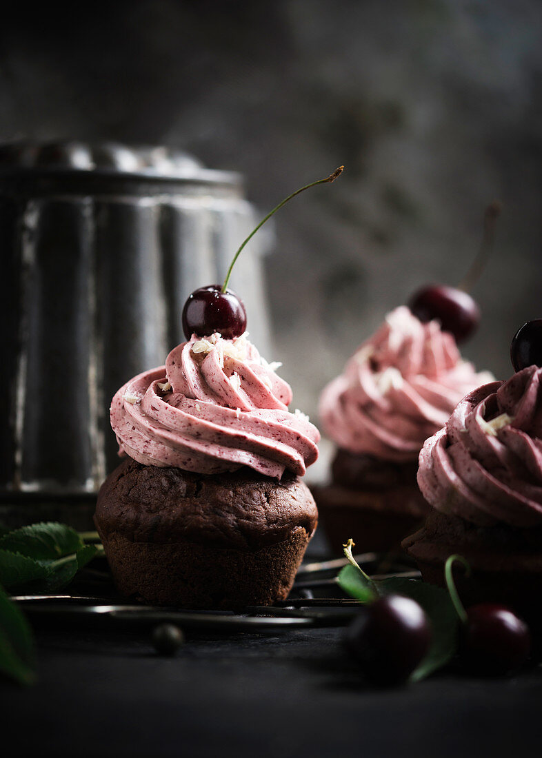 Vegan chocolate cupcakes topped with cherry butter cream frosting