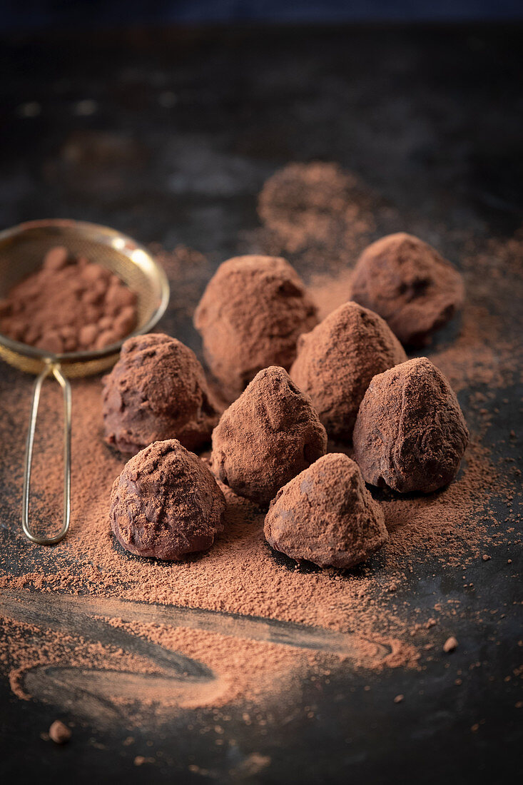Truffle pralines dusted with cocoa powder on a dark surface