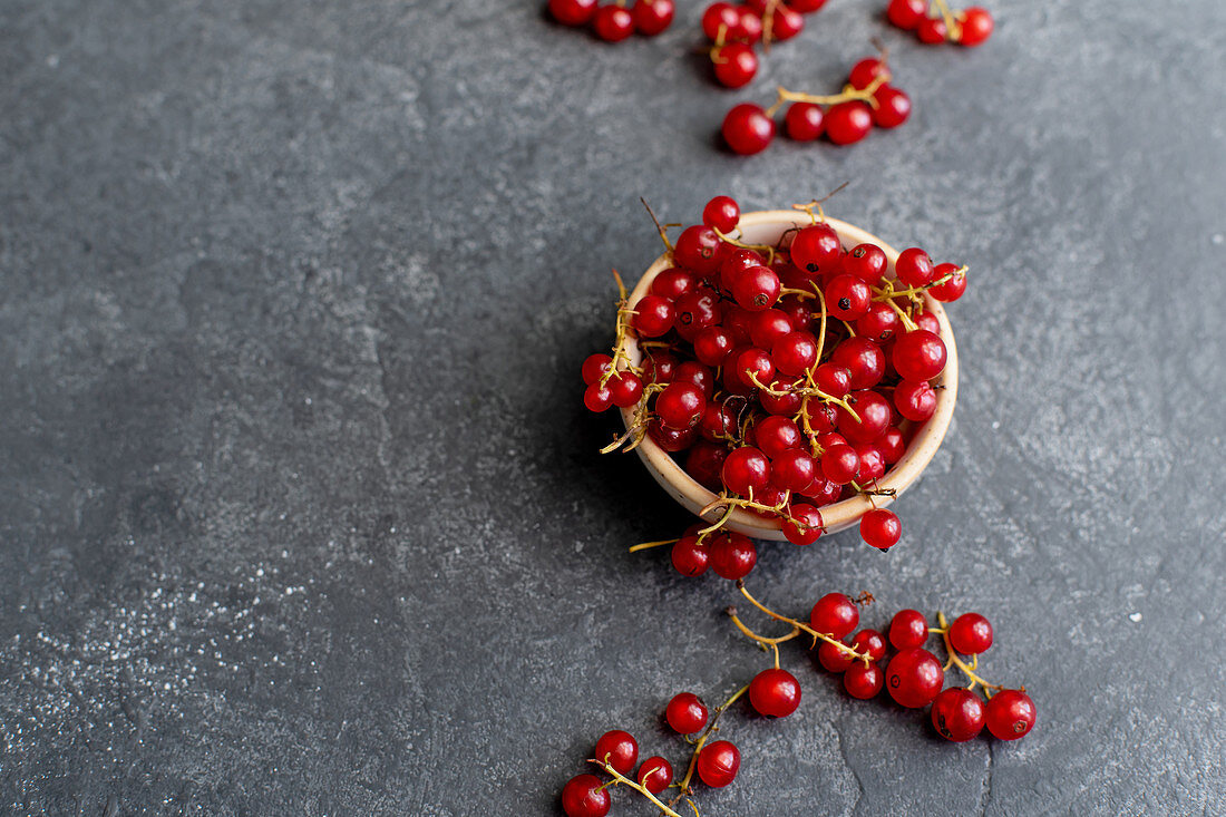 Redcurrant in a bowl on dark concrete background