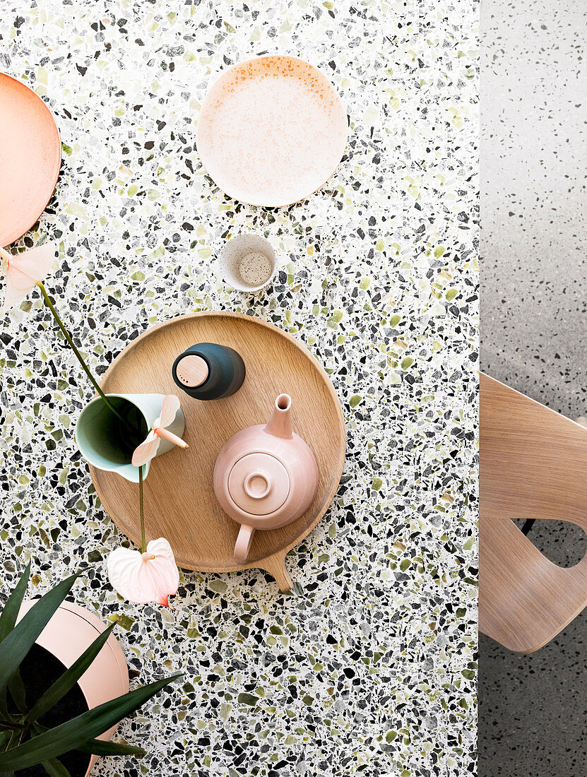 Top view of terrazzo table with tray, teapot and plates
