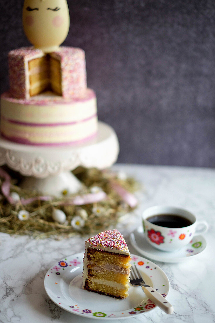 A slice of unicorn cake with a cup of coffee