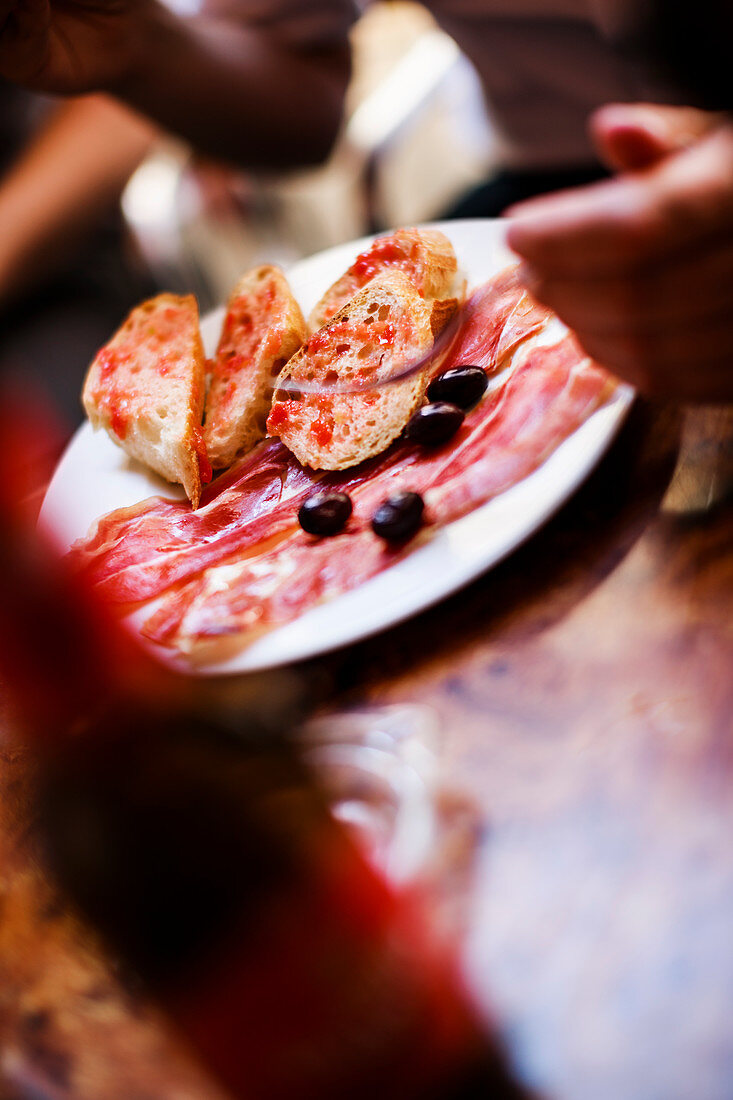 Tapas plate with prosciutto, olives and tomato bread