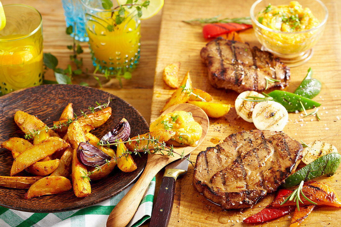 Spicy grilled pork collar steaks with potato wedges, grilled vegetables and a mango and tomato salsa