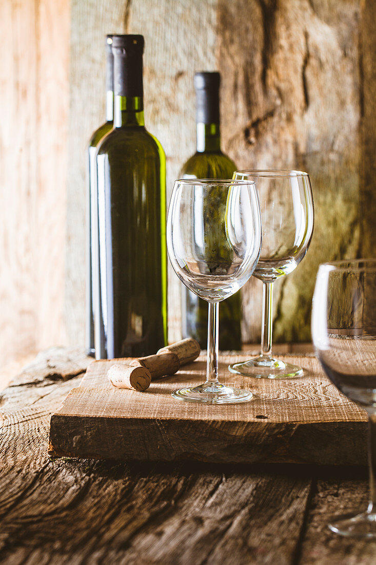 Rustikales Stilleben mit Weißweinflaschen und Gläsern