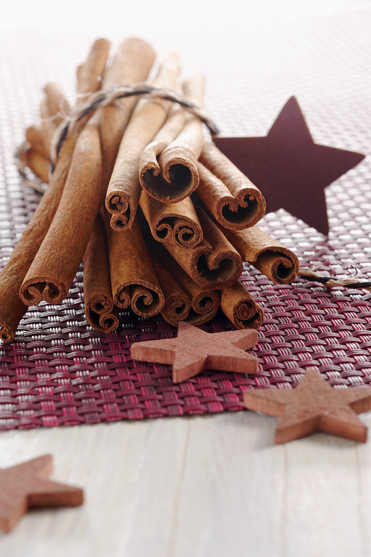 Cinnamon sticks and wooden stars on a purple surface