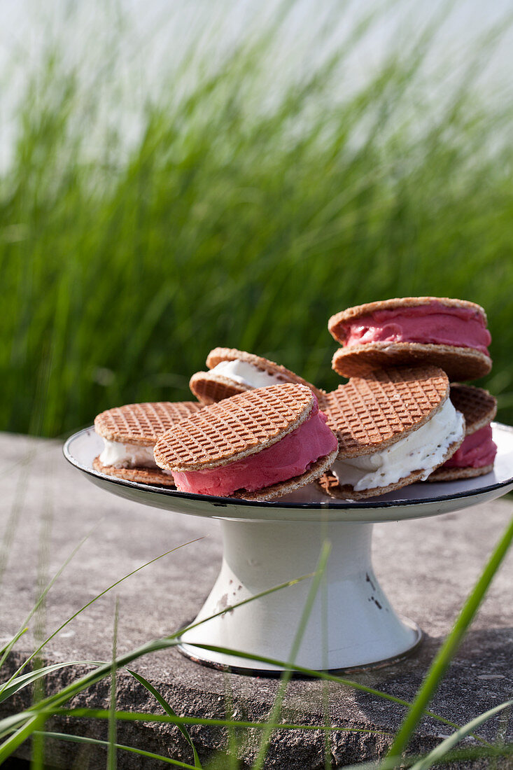 A cake stand with vanilla and raspberry ice cream sandwiches