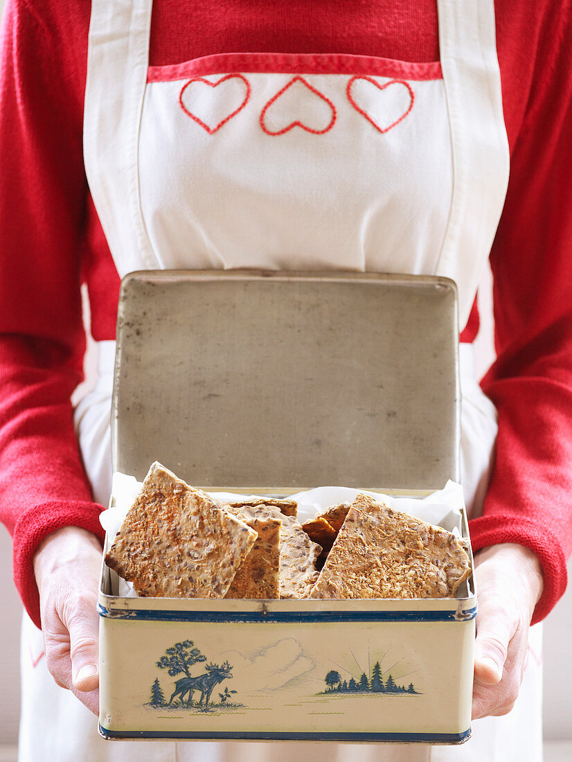 Frau hält Blechdose mit Knäckebrot