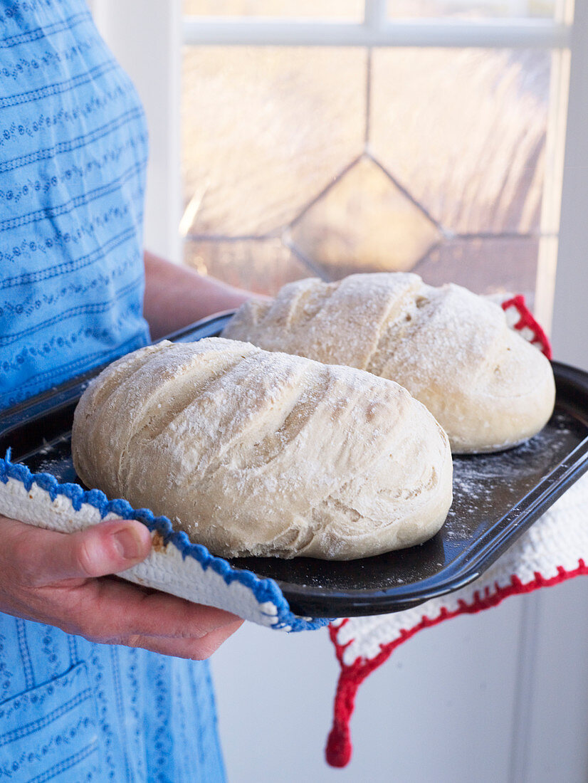 Frau hält Brot auf Backblech