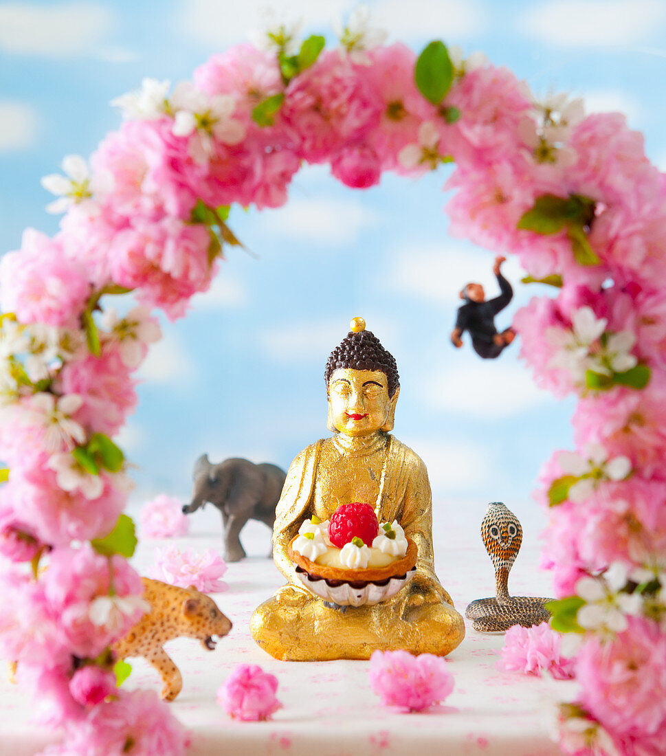 Buddha mit Himbeertörtchen und Blumendeko