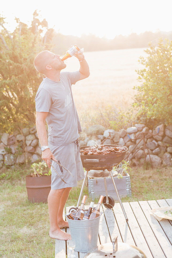 Mann trinkt Bier beim Grillen