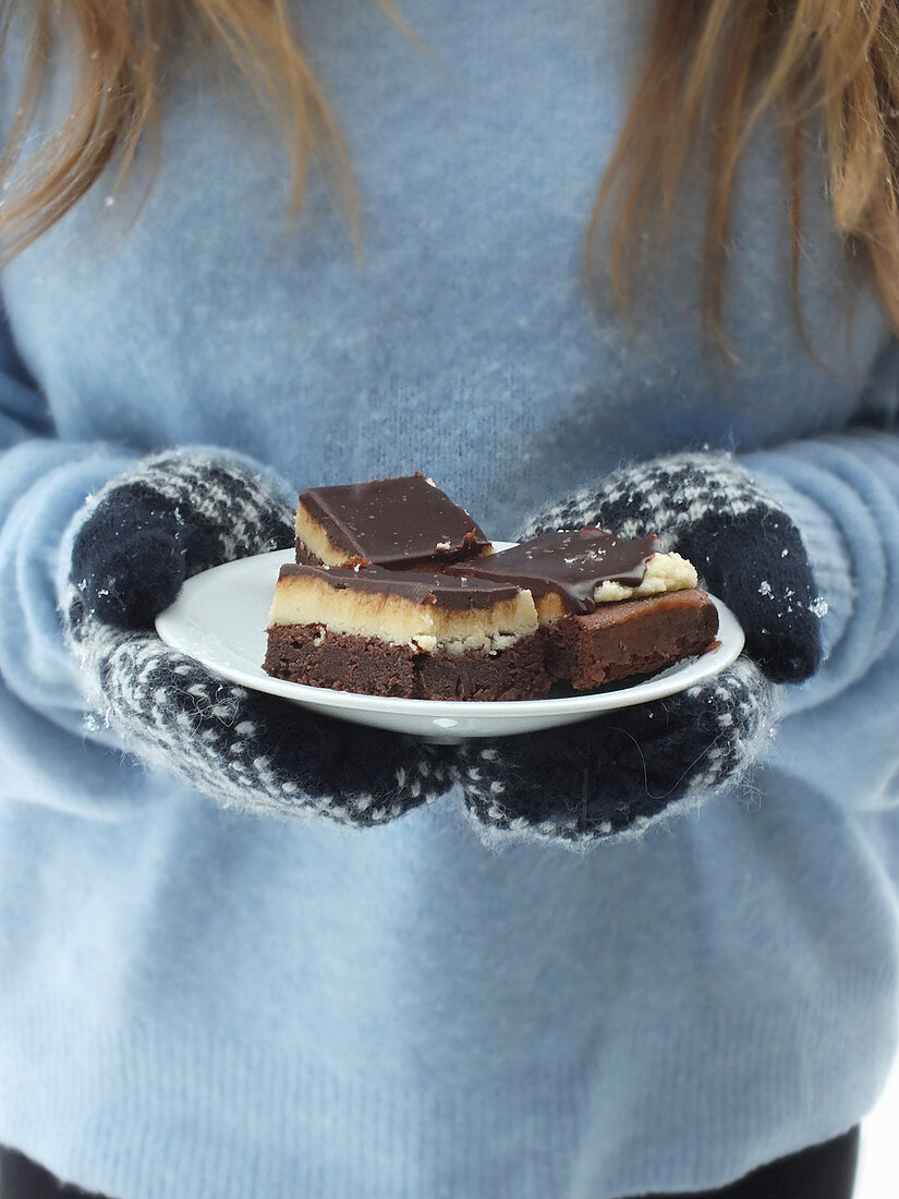 A woman wearing gloves holding a plate of chocolate semolina cake