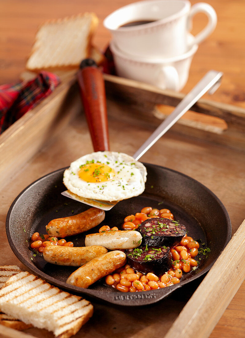 Scottish breakfast with baked beans, black pudding, bratwurst and a fried egg