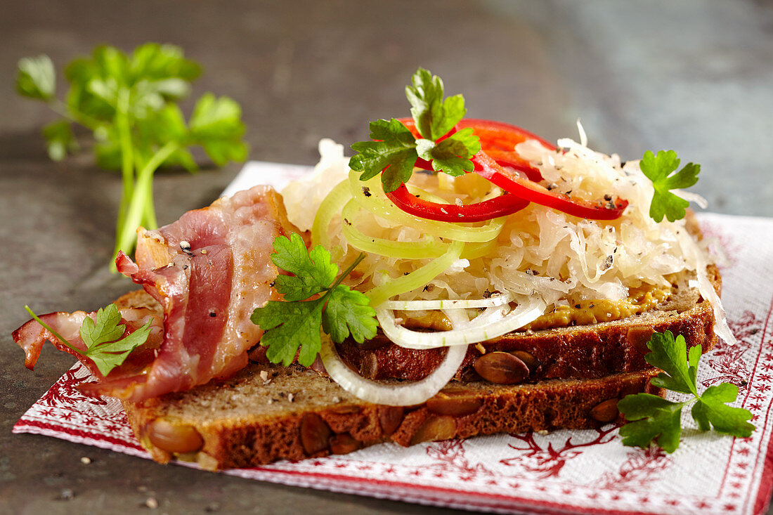 Vollkornbrot mit Senf, Sauerkraut, Bacon, Zwiebel und Paprika