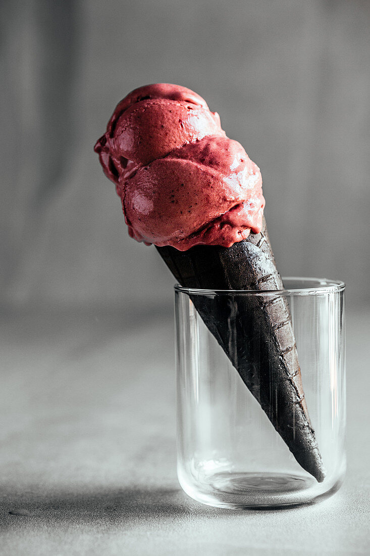 Erdbeer-Lakritz-Eis in schwarzer Eistüte