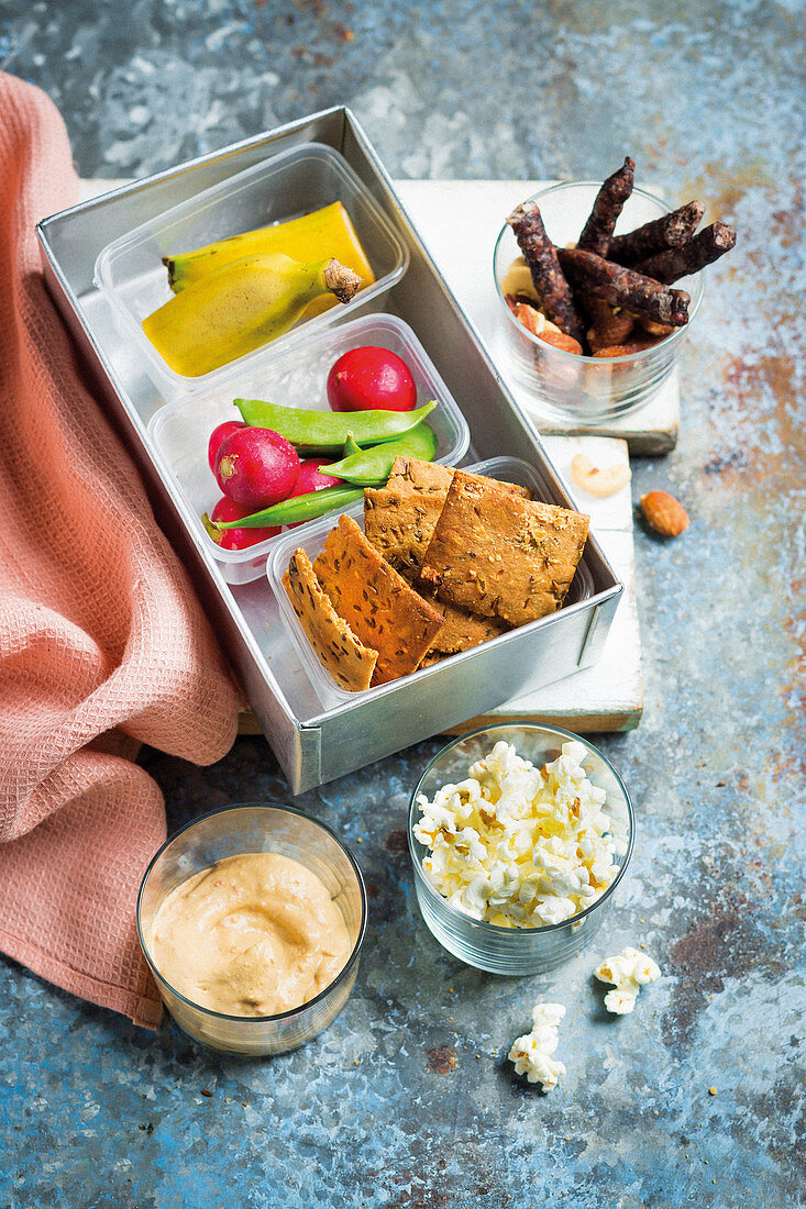 Lunchbox mit Crackern, Dips, Gemüse und Obst