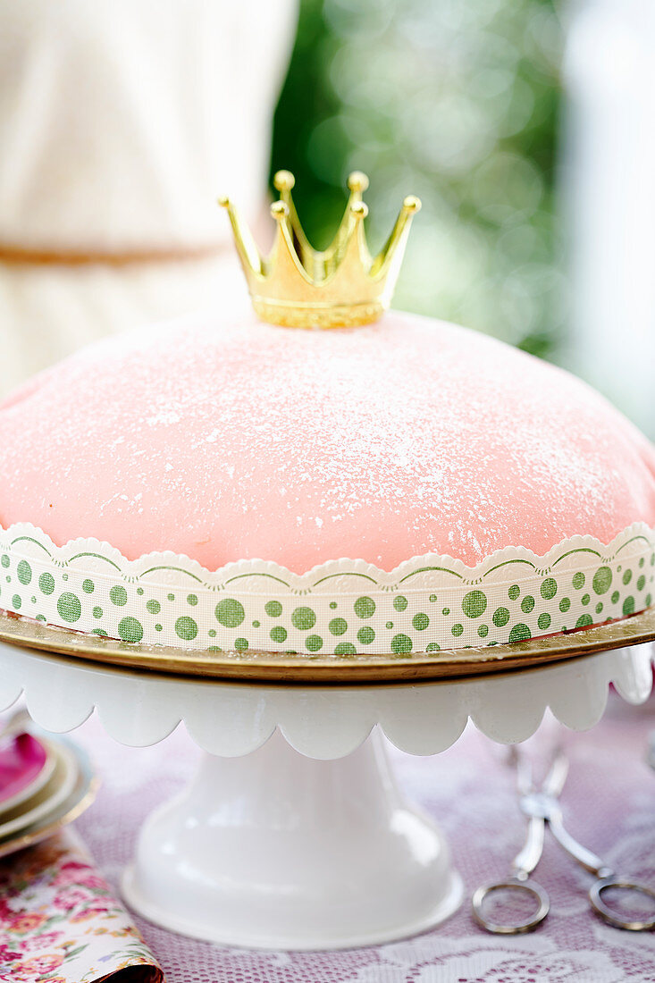 A pink princess cake on a cake stand