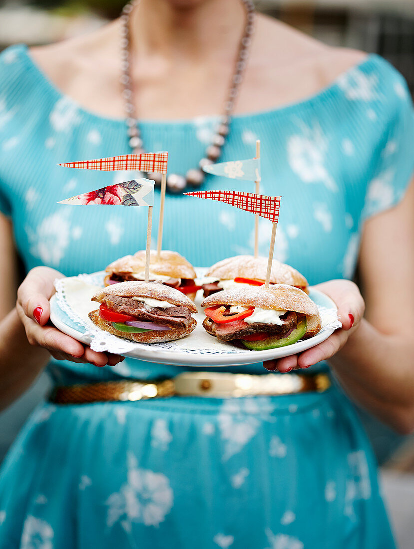Woman holding plate with sandwiches