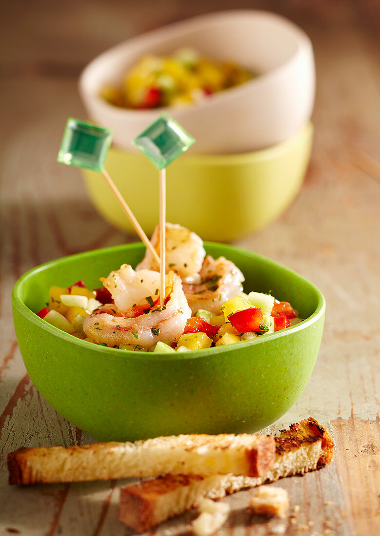 Summer party snack: mango and cucumber salad with fried shrimps and toasted bread