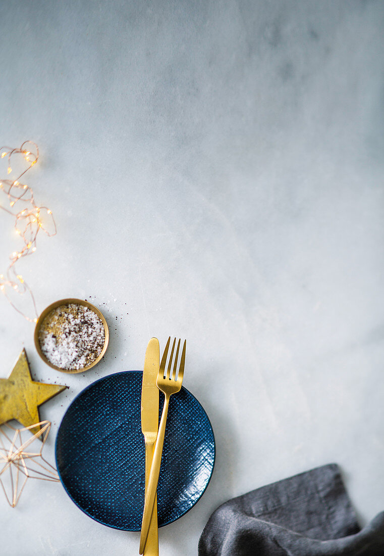 Blue dessert plate with golden cutlery, salt, pepper and Christmas decorations