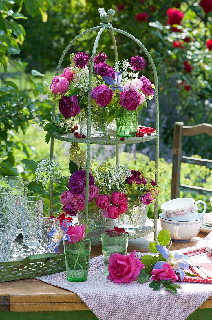 Etagere with small bouquets of roses, field chervil, scabious flower, lady's mantle and lupine as table decoration
