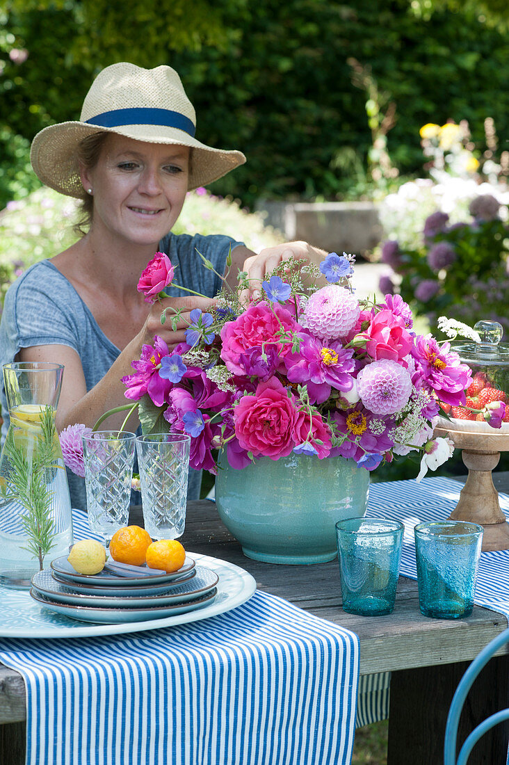 Woman puts an early summer bouquet with peonies, roses and dahlias