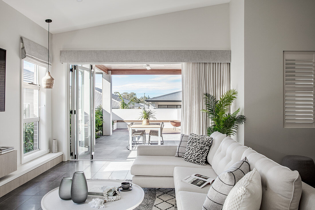 Pale sofa set with cushions and coffee table with view of roofed terrace in background