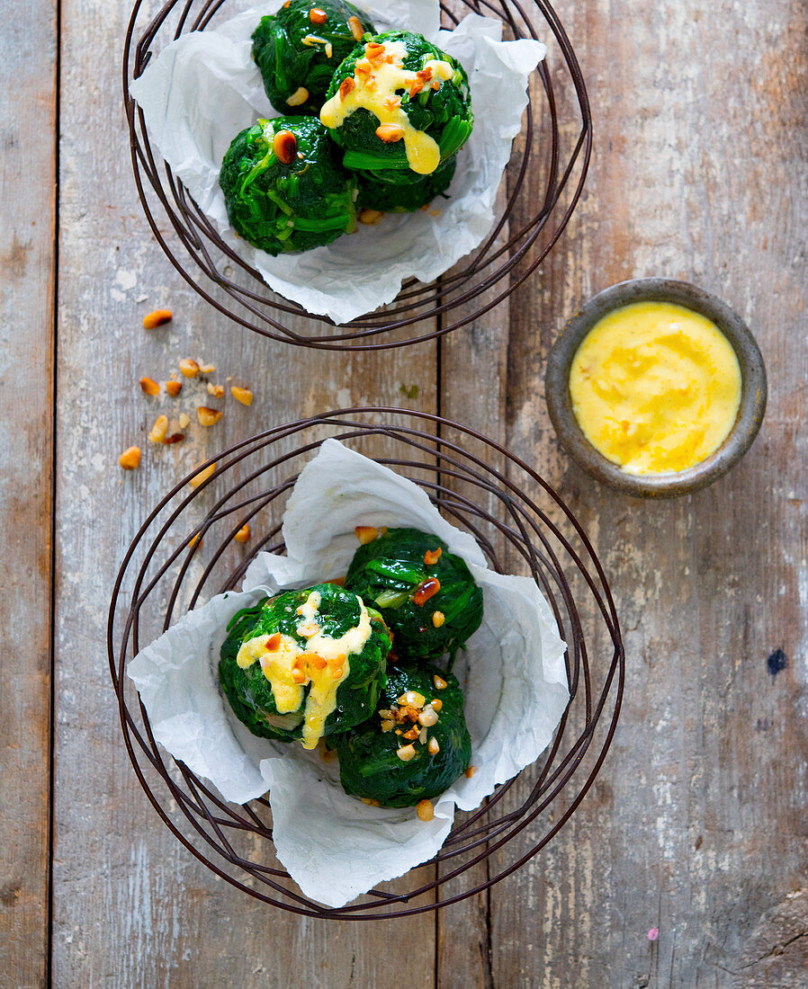 Spinach balls with hollandaise sauce and pine nuts
