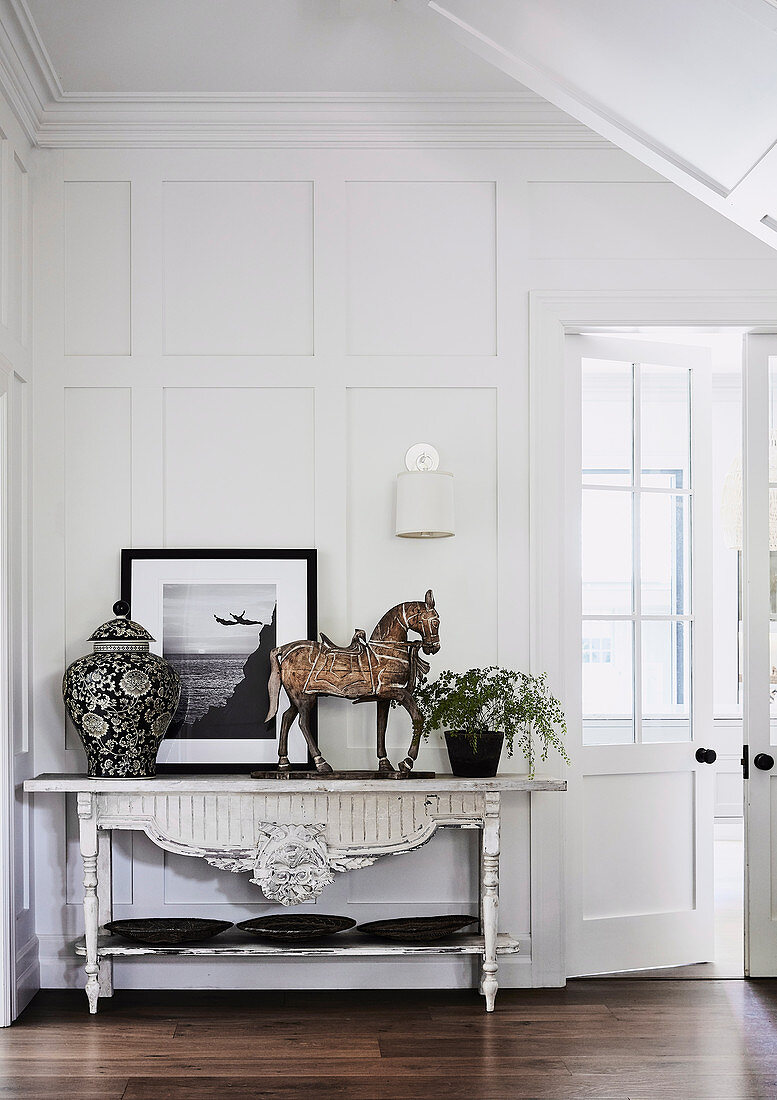 Antique console table with classical decoration in the hall with coffered wall