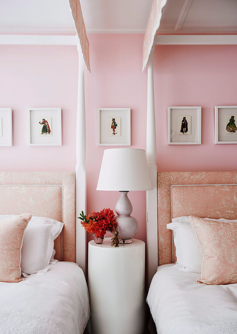 Round side table between two post beds in pink bedroom