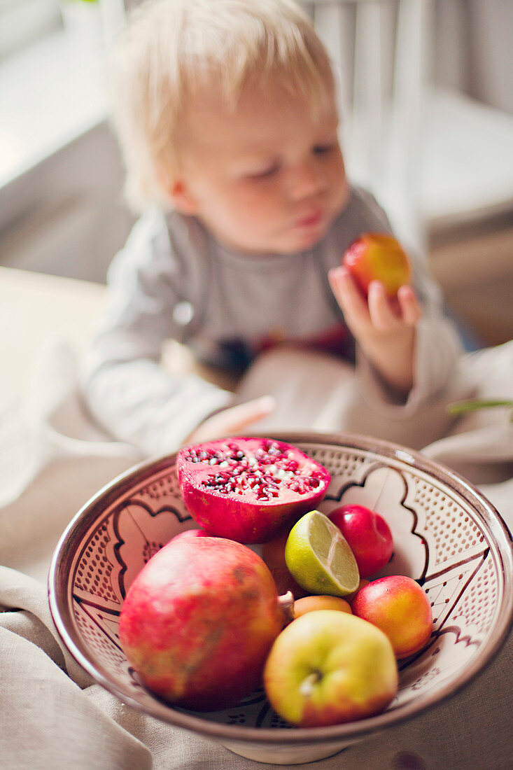 Kleiner Junge isst Obst aus einer Obstschale
