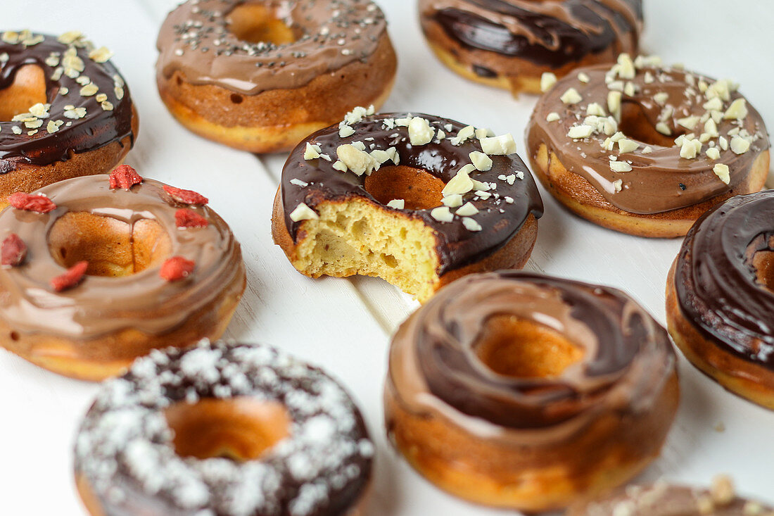 Verschiedene Donuts mit Schokoladenglasur, eins angebissen