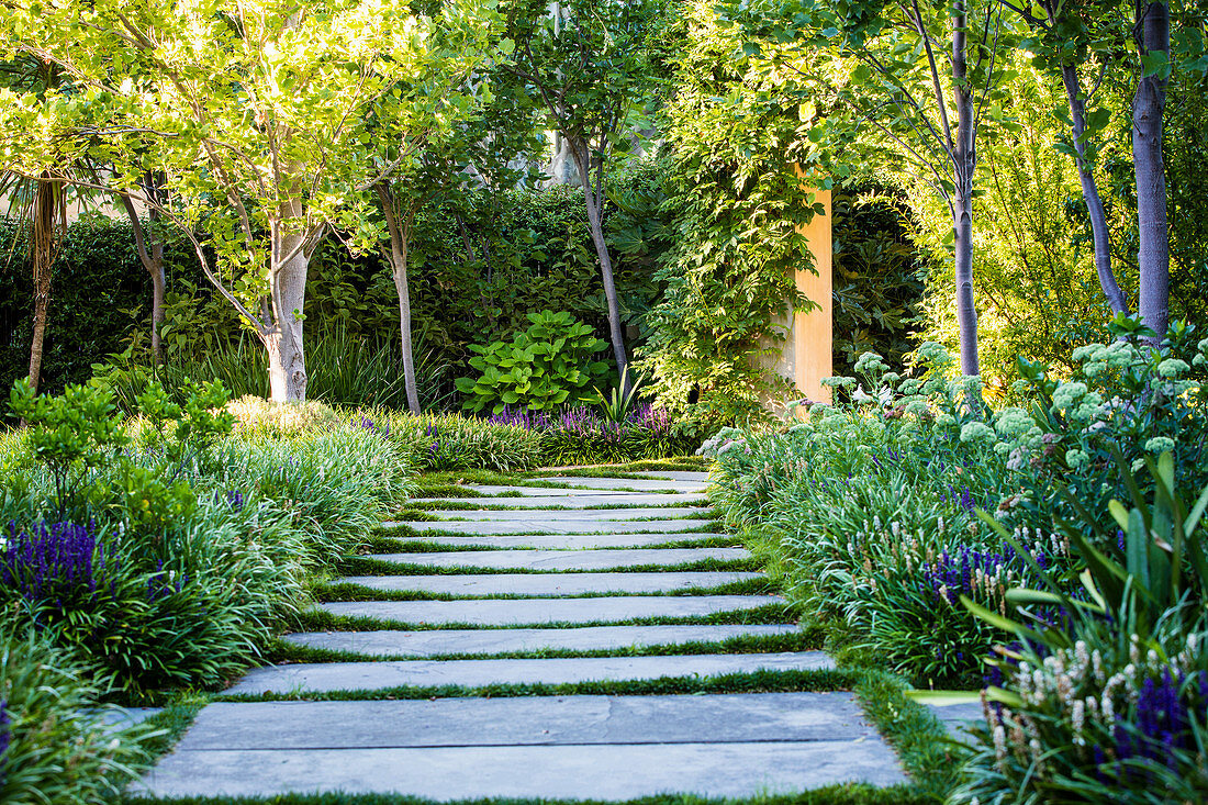 Weg aus großen Steinplatten durch sommerlichen Garten