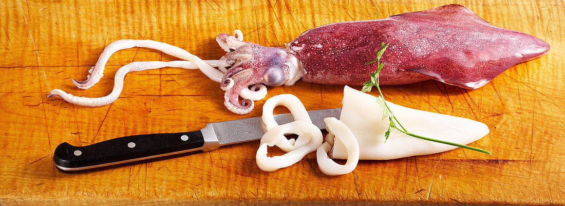 Roher Kalmar (Tintenfisch, Calamari) und Küchenmesser